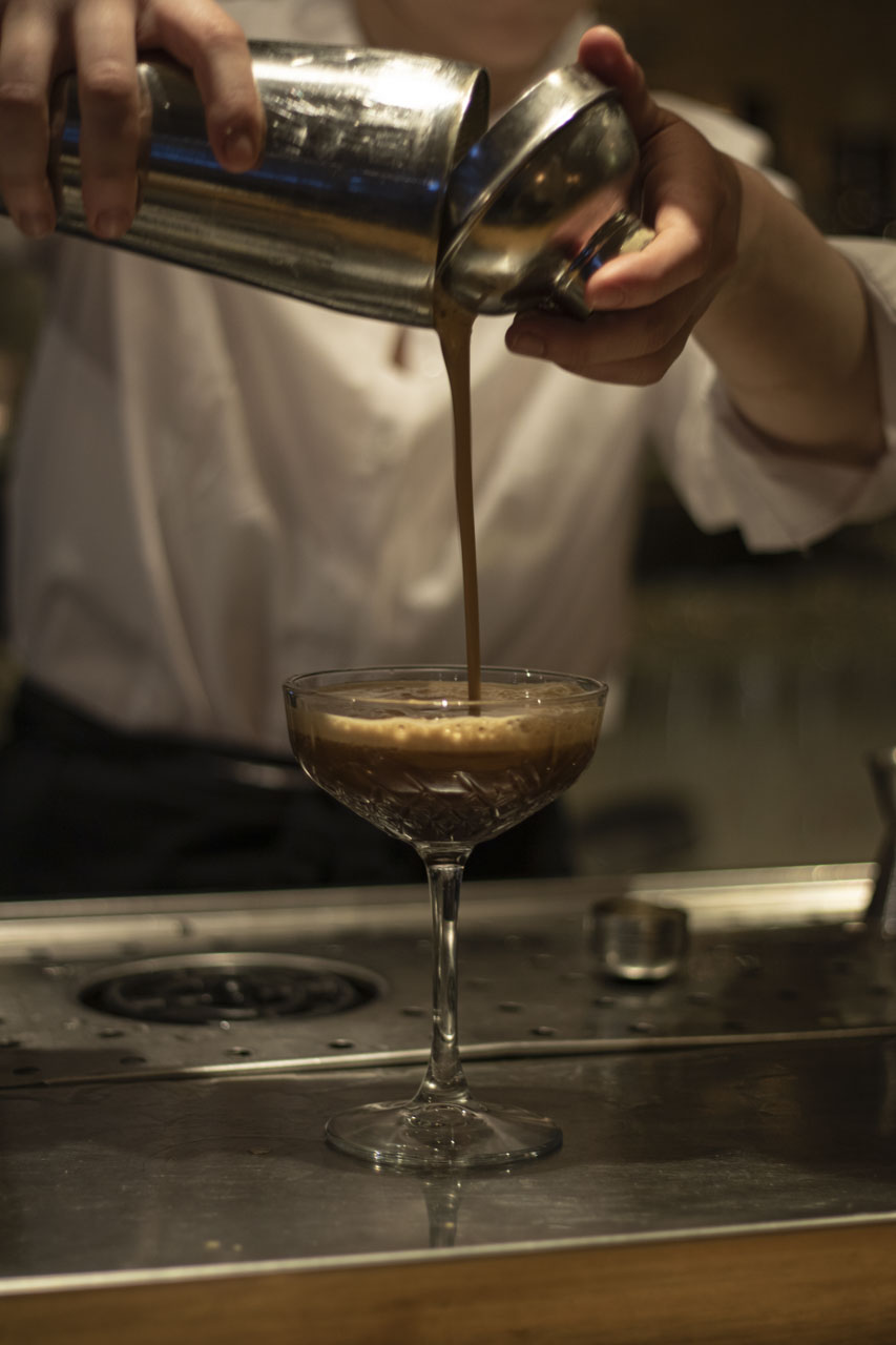 Een cocktail wordt aan de bar in een coupe geschonken bij Restaurant Maximiliano