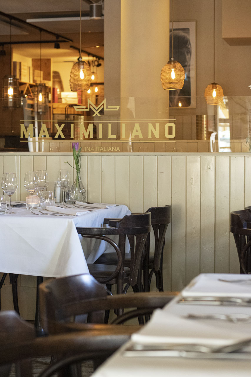 Het verlichte Maximiliano-bord boven de netjes gedekte tafels in het restaurant in Laren